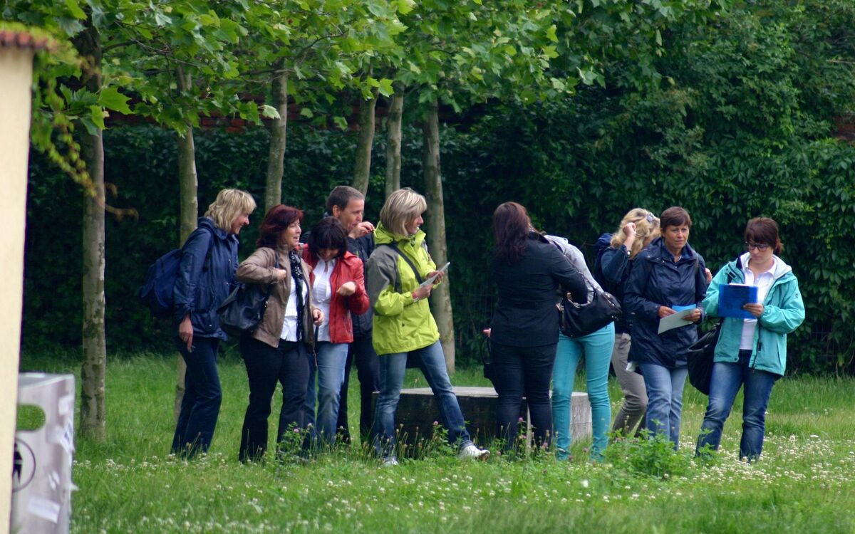 Teilnehmergruppe mit Karten bei einer Geocaching-Tour im Park