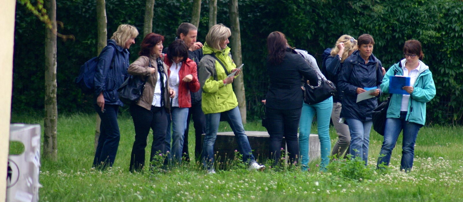 Teilnehmergruppe mit Karten und Arbeitsblättern bei einer Geocaching-Tour im Park